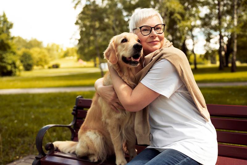 Woman hugging her dog on a park bench